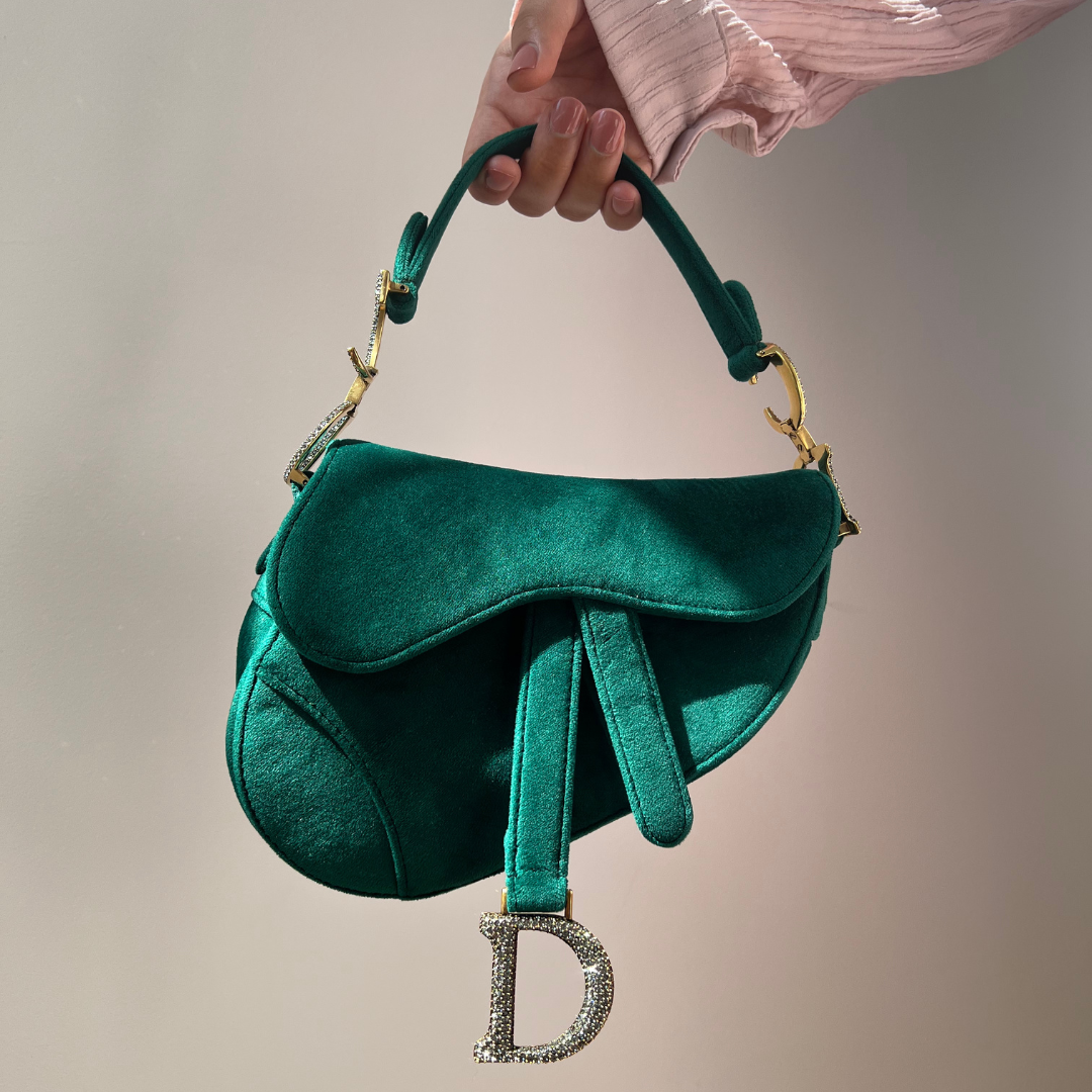 A hand holding a green Dior bag